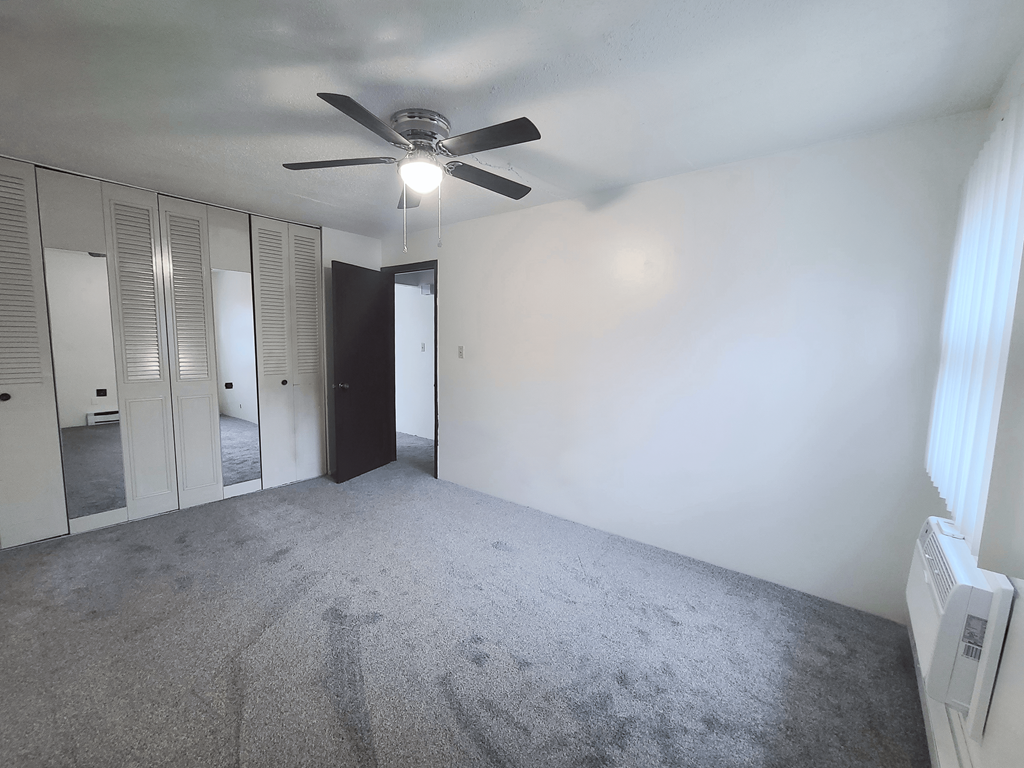 A room with a ceiling fan and carpeted floor.